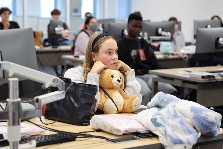 A student rests her head atop a toy used as part of the interactive lecture