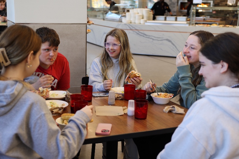 A group of students eat and laugh together